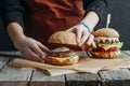 cropped view of girl in apron making homemade cheeseburgers on baking paper