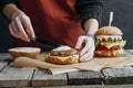 cropped view of girl in apron making tasty homemade cheeseburgers on baking paper