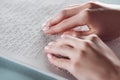 Cropped view of girl reading braille text with hands on white paper. Royalty Free Stock Photo