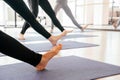 Cropped view of girls exercising yoga doing feet and legs stretching standing in a row Royalty Free Stock Photo