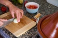 Cropped view of the hands of a chef cutting onion in two halves on a wooden board, using a kitchen knife. Royalty Free Stock Photo