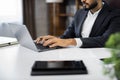 Cropped view of hands of young bearded businessman typing on laptop during work in office. Royalty Free Stock Photo