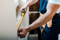 View of handyman measuring wall with yellow measuring tape