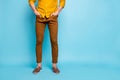 Cropped view of his he young guy wearing brown pants orange formal casual shirt holding hands in pockets  on Royalty Free Stock Photo