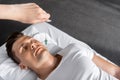 View of hypnotist standing near man on massage table and holding green stone