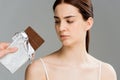 View of man holding chocolate bar near brunette upset woman with acne  on grey Royalty Free Stock Photo