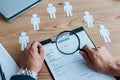 View of man holding magnifier near clipboard with resume