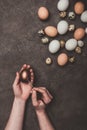 Man painting golden easter egg, quail and chicken eggs near