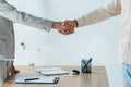 View of man and recruiter shaking hands near table