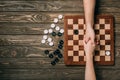 Cropped view of man and woman shaking hands above checkerboard with checkers