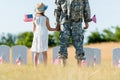View of military man and patriotic child holding hands and american flags