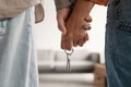 Cropped view of millennial couple holding hands and key to new home, moving in together. Mortgage for young families Royalty Free Stock Photo