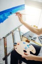 Woman artist painting a picture in a well-lit studio Royalty Free Stock Photo