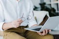 Cropped view of pensioner holding glasses and using laptop