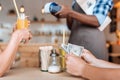 cropped view of people paying with cash, waiter standing behind