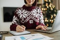 Cropped view pf woman hand with pen in Santa hat making notes on paper document