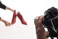 Cropped view of photographers making commercial photo shoot of female red heel shoes on white