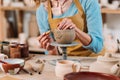 cropped view of potter in apron decorating ceramic bowl