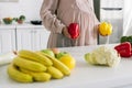 View of pregnant woman holding paprika standing near fruits on table Royalty Free Stock Photo