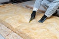 Professional workman installing thermal insulation layer with fiberglass wool under the roof