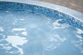 Cropped view of a round outdoor swimming pool with blue mosaic ceramic tiles, with blue water. Background with copy Royalty Free Stock Photo