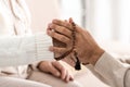 cropped view of senior man with rosary breads holding hands with wife.