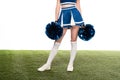 View of sexy cheerleader girl in blue skirt and gaiters with pompoms on green field isolated on white Royalty Free Stock Photo