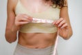 Cropped view of slim woman measuring breasts with tape measure at home, close up. Unrecognizable European woman checks Royalty Free Stock Photo