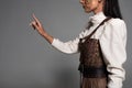 View of steampunk young woman in white blouse gesturing on grey