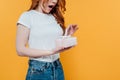Cropped view of surprised redhead girl holding gift box isolated on yellow with copy space. Royalty Free Stock Photo