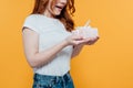 Cropped view of surprised redhead girl holding gift box isolated on yellow with copy space. Royalty Free Stock Photo