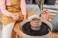 cropped view of teacher and kid painting ceramic pot on pottery wheel Royalty Free Stock Photo