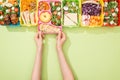 Cropped view of woman choosing lunch boxes with food on green background. Royalty Free Stock Photo