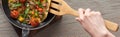 Cropped view of woman cooking omelet with mushrooms and tomatoes on frying pan with wooden shovel. Royalty Free Stock Photo