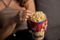 Cropped view of a woman eating popcorn. Girl enjoys snack while chilling at home Royalty Free Stock Photo