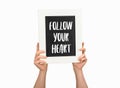 Cropped view of woman holding chalkboard with inscription follow your heart