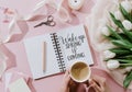 cropped view of woman holding coffee cup on pink surface with tulips and WAKE UP Royalty Free Stock Photo