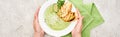 Cropped view of woman holding plate with delicious creamy green vegetable soup with croutons near green napkin Royalty Free Stock Photo