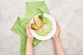 Cropped view of woman holding plate with delicious creamy green vegetable soup with croutons near green napkin.