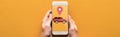Cropped view of woman holding smartphone with rent car app on orange background, panoramic shot. Royalty Free Stock Photo