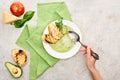 Cropped view of woman holding spoon near plate with delicious creamy green vegetable soup with croutons.