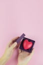 Cropped view of woman holding valentines gift box with heart on pink background. Health care, donate concept