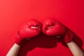 Cropped view of woman in pair of boxing gloves on red .