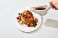 Cropped view of woman pouring maple syrup on delicious pancakes with blueberries and strawberries on plate on marble white surface Royalty Free Stock Photo