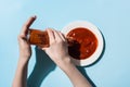 Cropped view of woman pouring tomato sauce from bottle to plate on blue background Royalty Free Stock Photo