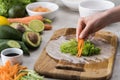 Cropped view of woman putting cut carrot on lettuce, on cutting board. Royalty Free Stock Photo