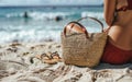 A cropped view of a woman in red swimwear with a straw bag and sandals on the sandy beach Royalty Free Stock Photo