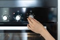 Woman hand turning switch at modern built in oven and select program