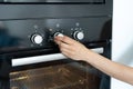 Woman select program turning switch at modern built in oven