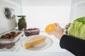 Cropped view of woman taking orange slice from fridge with food  on white Royalty Free Stock Photo
